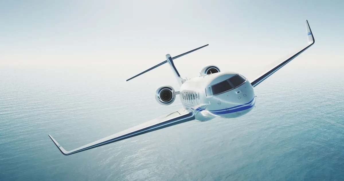 A private jet flying over a calm blue sea